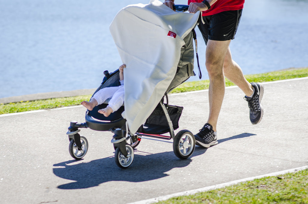 Man running with pram covered with musluv baby sun shade cover