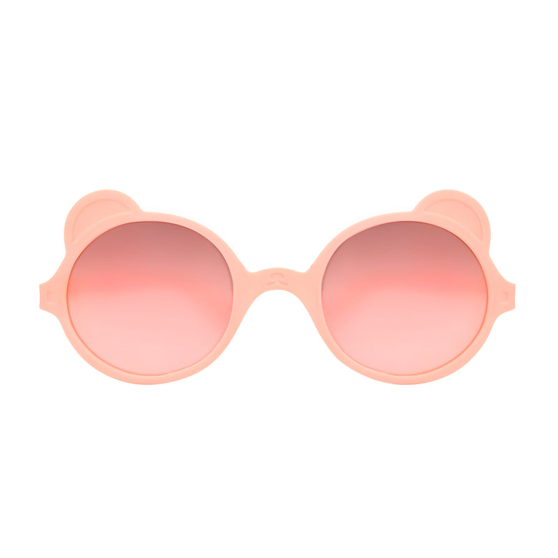 Front view of peach-coloured baby sunglasses with teddy ear and nose detailing